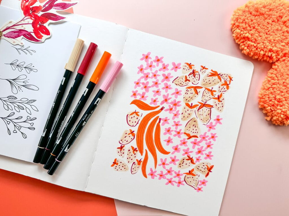 Artistic drawing in a sketchbook with floral patterns on a notebook with markers.