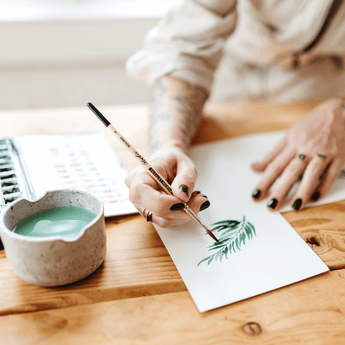 An artist painting delicate leaves in watercolor